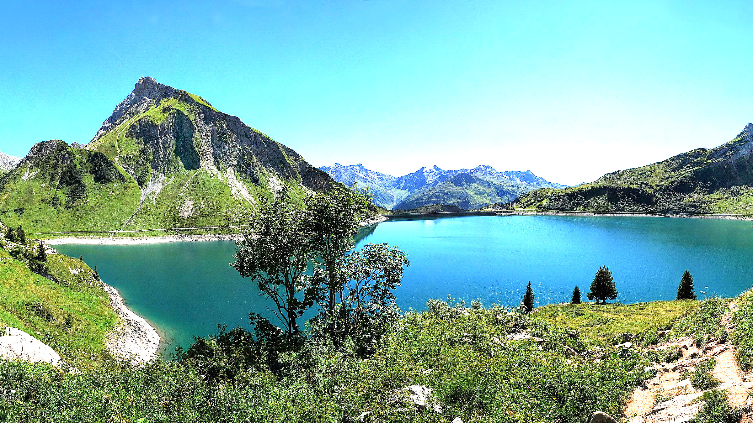Ruhiger österreichischer See mit Uferort und bewaldeten Hängen